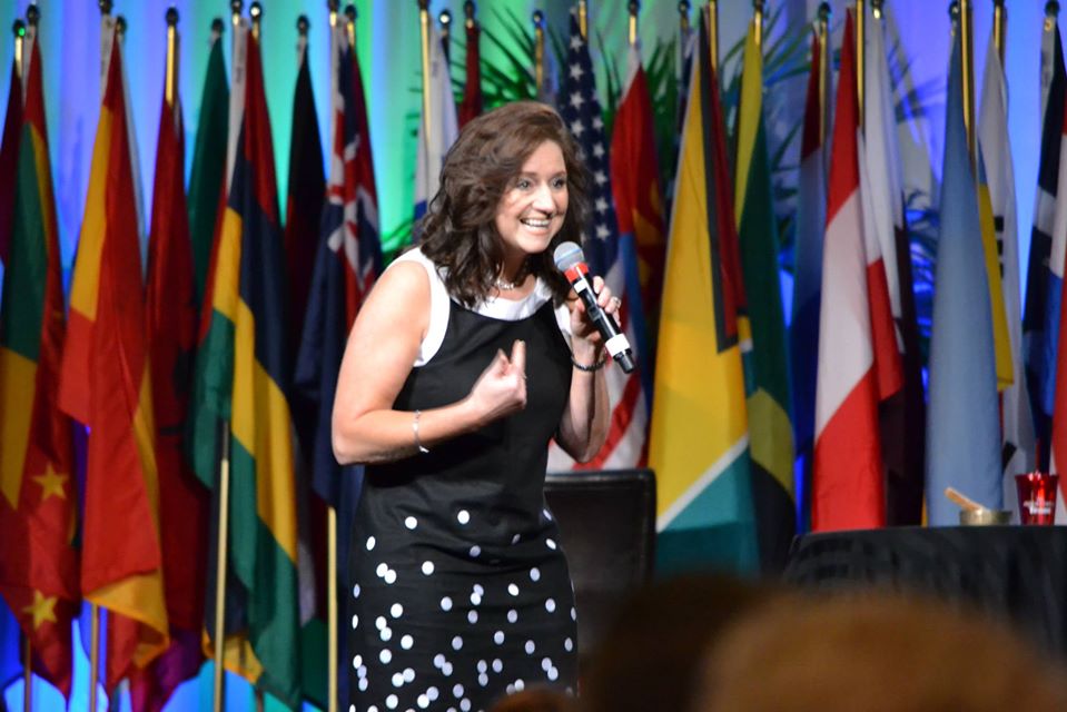 Shari Strong speaking on stage in front of international flags